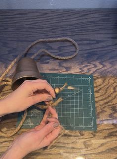 someone is working on something with scissors and a piece of string attached to the table