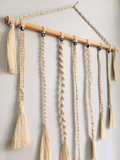 macrame wall hangings with tassels and beads on them, hung on a white wall