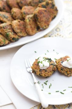 two white plates with food on them next to a platter of meat patties