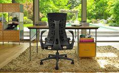 an office area with a desk, chair and large window looking out onto the backyard