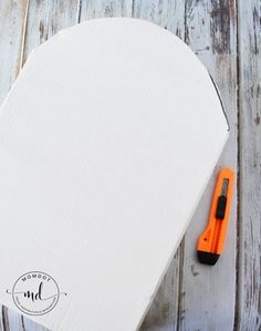 an orange pen sitting on top of a piece of paper next to a white box