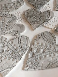 several pieces of lace are laid out on a white tablecloth, which is decorated with intricate designs