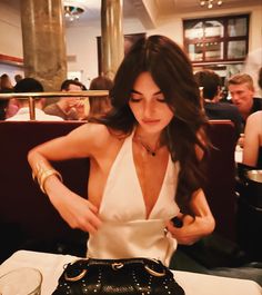 a woman sitting at a table in front of a purse