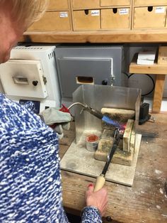 a woman is making something out of some kind of wood with a knife and other tools