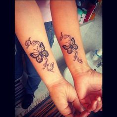 two girls with matching butterfly tattoos on their arm and wrist, both holding hands together