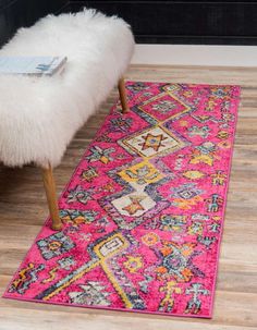 a bright pink rug with an ornate design on the floor next to a white bench