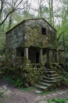 an old stone building with moss growing on it's walls and steps leading up to the door