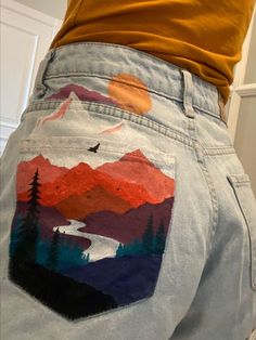 the back of someone's jeans with mountains and trees painted on them