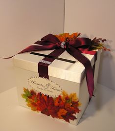 a white gift box with autumn leaves on it