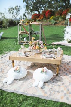 a picnic table set up for two with stuffed animals and flowers on the rugs