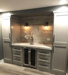 an empty kitchen with gray cabinets and white counter tops in the center is a vase with flowers on it