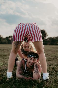 a man and woman laying in the grass with their legs up on each other's heads