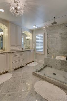 a large bathroom with marble flooring and white cabinetry on the walls, along with a walk in shower