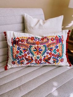 a white couch with a colorful embroidered pillow on it