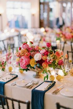 the tables are set with white linens, blue tablecloths and colorful floral centerpieces