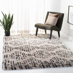 a chair sitting on top of a white rug next to a potted green plant