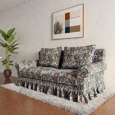 a living room filled with furniture and a plant on top of a hard wood floor