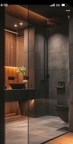 an image of a bathroom setting with glass walls and wood flooring in the shower area