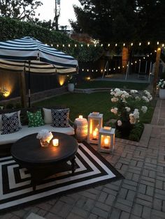 an outdoor seating area with lit candles on the table and in the background is a gazebo