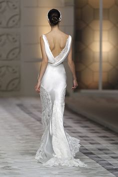 a woman walking down a runway in a white dress with a backless neckline