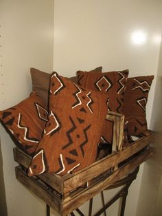 some brown and white pillows in a wooden crate on top of a table next to a wall