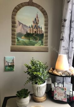 there is a potted plant on the table in front of a window with a castle painted on it