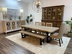 a dining room table with two benches in front of it and an area rug on the floor