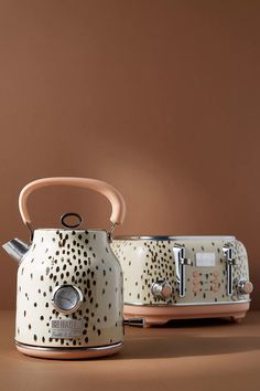 two tea kettles sitting next to each other on a brown surface with polka dots