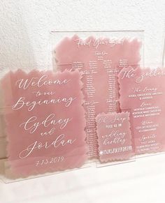 pink and white wedding programs displayed in clear acrylic