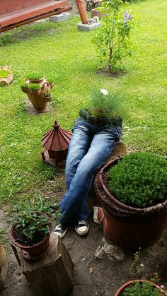 a man is sitting in the grass with his head down next to some potted plants