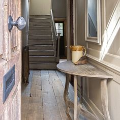 an open door leading to a hallway with stairs and a cup on a table in front of it