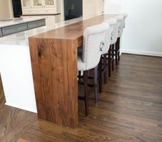 a kitchen with an island made out of wood and white chairs