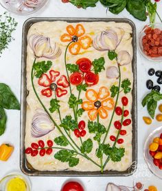 an assortment of vegetables and fruits laid out on a white table with a baking sheet