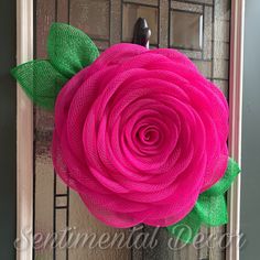 a pink rose with green leaves is hanging on the front door to show it's beautiful colors