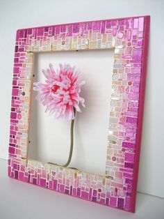 a pink flower is in a mosaic frame