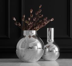 two silver vases sitting on top of a marble countertop next to each other