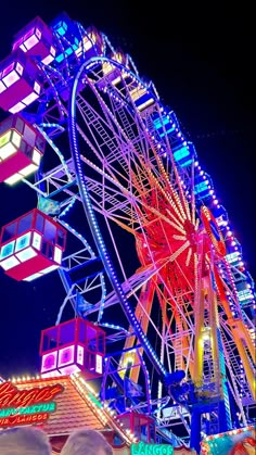 the ferris wheel is brightly lit up at night