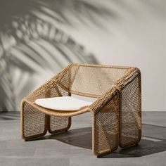 a chair made out of wicker with a white cushion