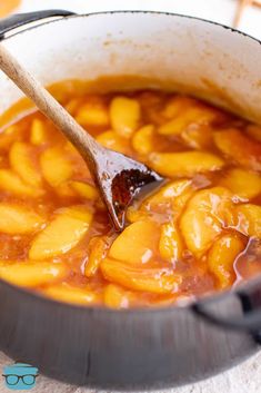 a wooden spoon in a pot filled with food and sauce on top of a table