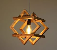 a wooden light fixture hanging from the ceiling with an electric bulb in it's center