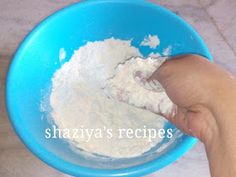 a hand is holding a blue bowl with flour in it