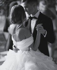 a man in a tuxedo and a woman in a wedding dress dance together