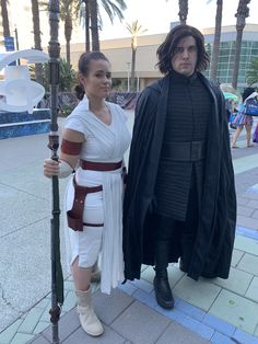 two people dressed up as star wars characters standing next to each other on the sidewalk