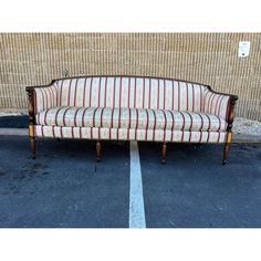 a couch sitting in the middle of a parking lot next to a wall with stripes on it