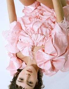 a woman in a pink dress laying on the ground with her legs spread out and hands behind her head