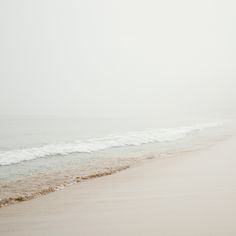 two people walking on the beach with an umbrella