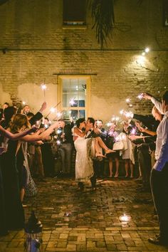 a bride and groom are surrounded by their guests with sparklers