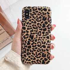 a woman's hand holding up a phone case with leopard print on the back