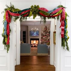 a living room decorated for christmas with red, green and blue ribbons hanging from the ceiling