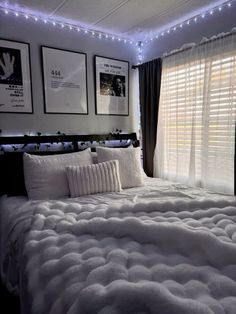 a bed with white comforter and pillows in a room decorated with pictures on the wall